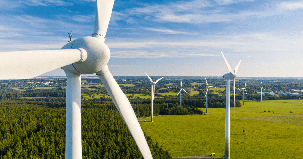 Wind Turbines In A Green Field With Blue Sky
